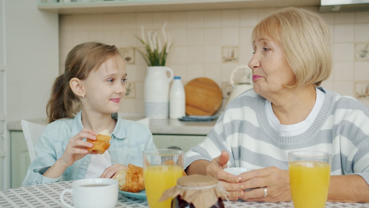 Grandmother and granddaughter sharing breakfast, laughing together